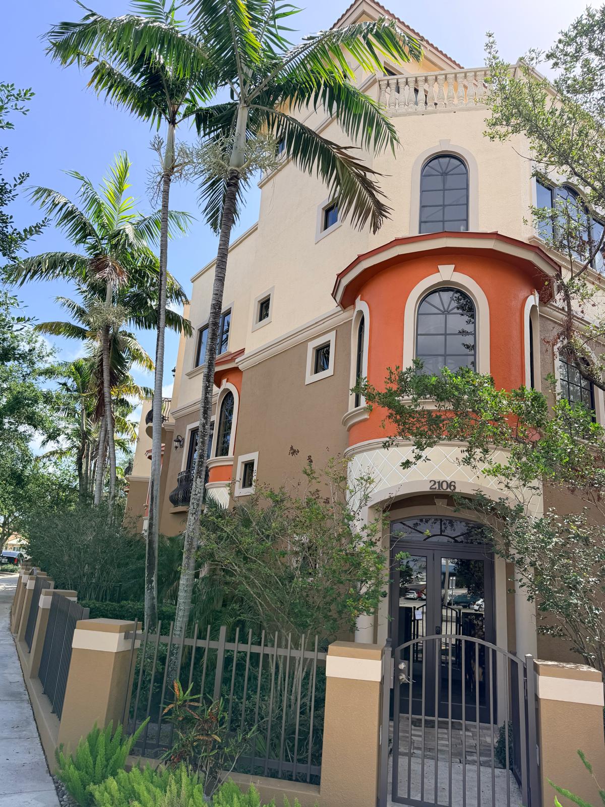 A vibrant multi story residential building with freshly painted stucco exterior and prominent palm trees.
